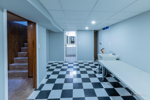 interior space featuring baseboards, dark floors, stairs, a paneled ceiling, and a sink