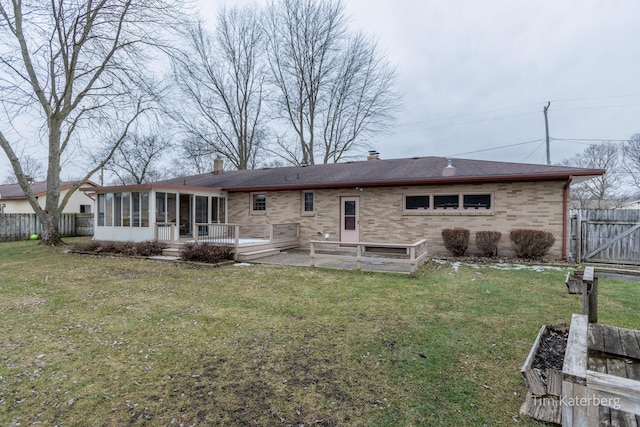 rear view of house featuring a sunroom, brick siding, a yard, and fence