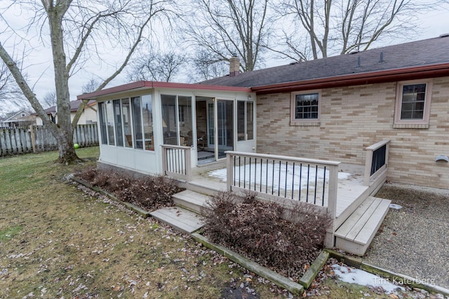 exterior space with a sunroom, a chimney, fence, a yard, and brick siding