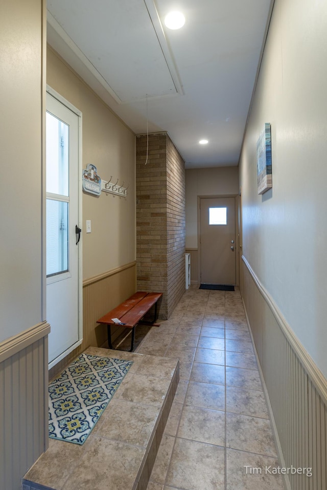 doorway to outside with wainscoting and light tile patterned floors