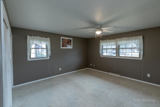 carpeted empty room with ceiling fan, baseboards, visible vents, and a healthy amount of sunlight