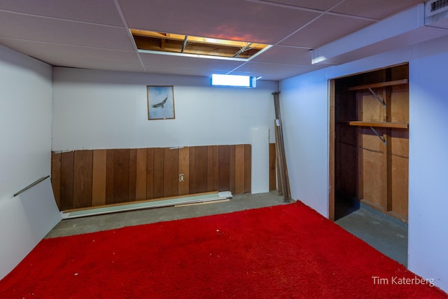 finished below grade area featuring a paneled ceiling and wooden walls