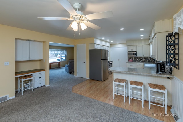 kitchen with stainless steel appliances, a peninsula, a sink, decorative backsplash, and built in desk