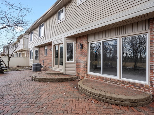 rear view of house featuring brick siding, a patio, central AC, and fence