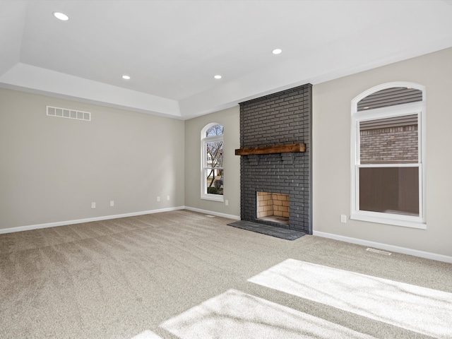 unfurnished living room featuring a tray ceiling, visible vents, a fireplace, and baseboards