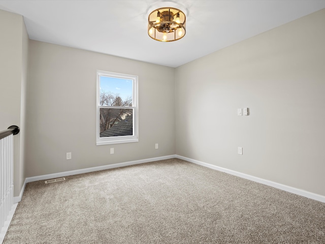 spare room with carpet floors, visible vents, and baseboards