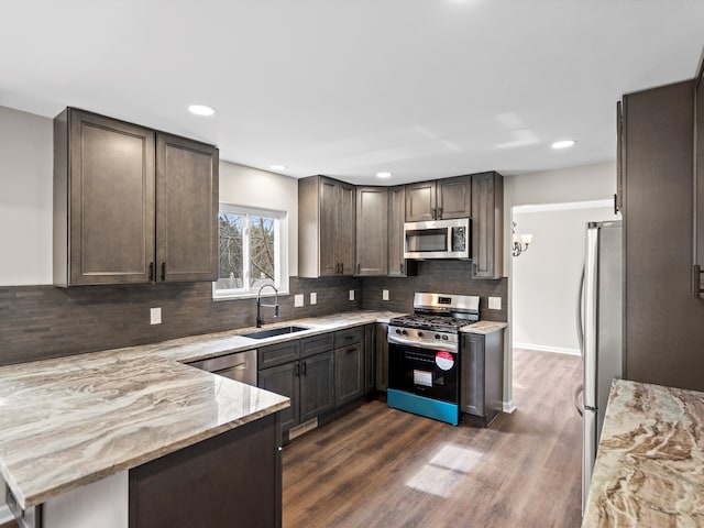 kitchen with tasteful backsplash, dark wood finished floors, light stone counters, stainless steel appliances, and a sink