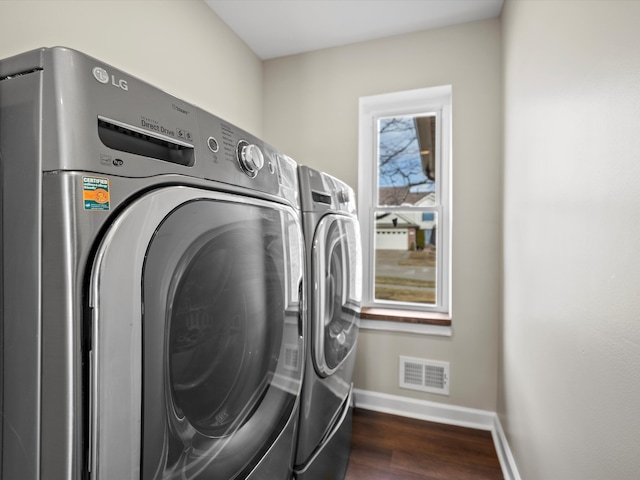 laundry room with laundry area, visible vents, dark wood finished floors, and washer and dryer