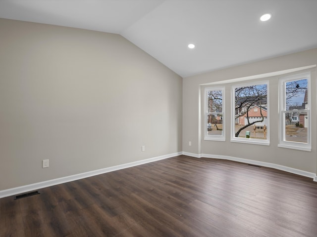 unfurnished room featuring vaulted ceiling, dark wood-type flooring, visible vents, and baseboards