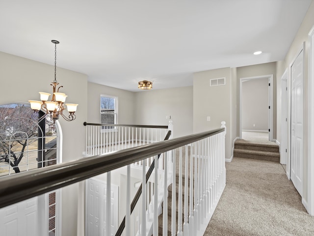 hall with visible vents, an inviting chandelier, light carpet, an upstairs landing, and baseboards