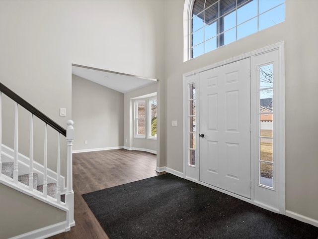 foyer entrance featuring stairs, dark wood finished floors, a towering ceiling, and baseboards