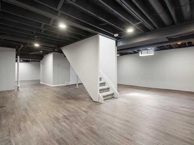 finished basement featuring stairway, wood finished floors, and visible vents