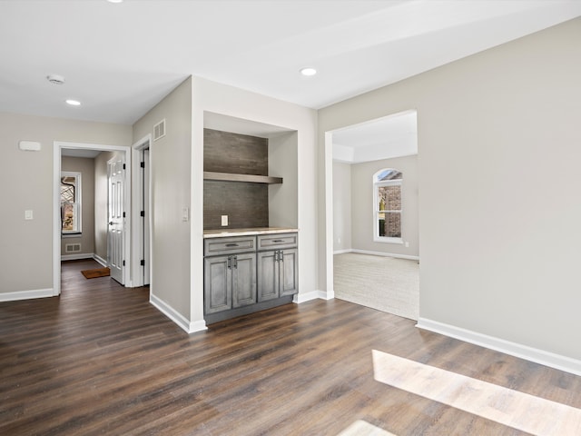 interior space featuring dark wood-type flooring, visible vents, and baseboards