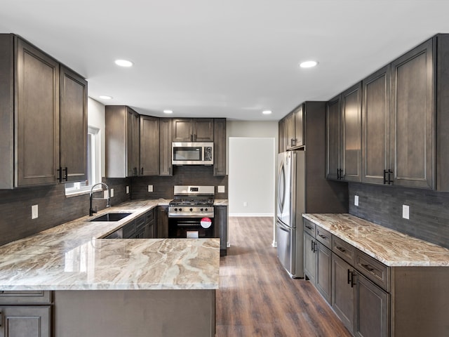 kitchen featuring dark wood finished floors, appliances with stainless steel finishes, light stone counters, and a sink