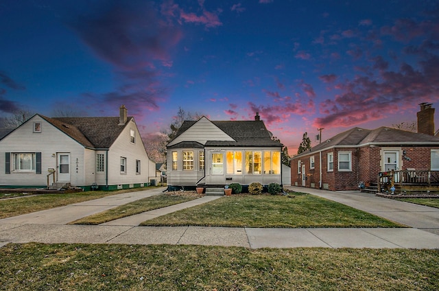 bungalow with covered porch, concrete driveway, and a lawn