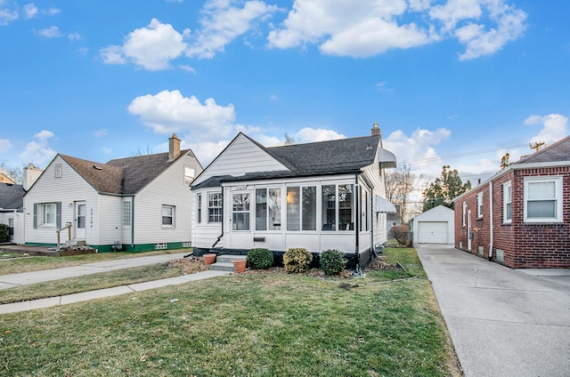 bungalow-style home with an outbuilding, entry steps, a detached garage, driveway, and a front lawn