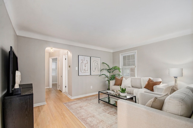 living room featuring light wood-style floors, baseboards, and arched walkways