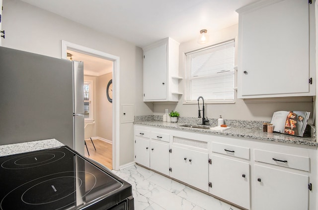 kitchen with white cabinets, black electric range oven, freestanding refrigerator, marble finish floor, and a sink