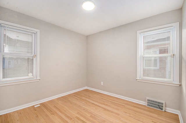 empty room featuring light wood finished floors, visible vents, and baseboards