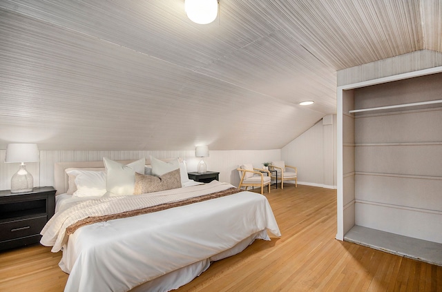 bedroom with vaulted ceiling and wood finished floors