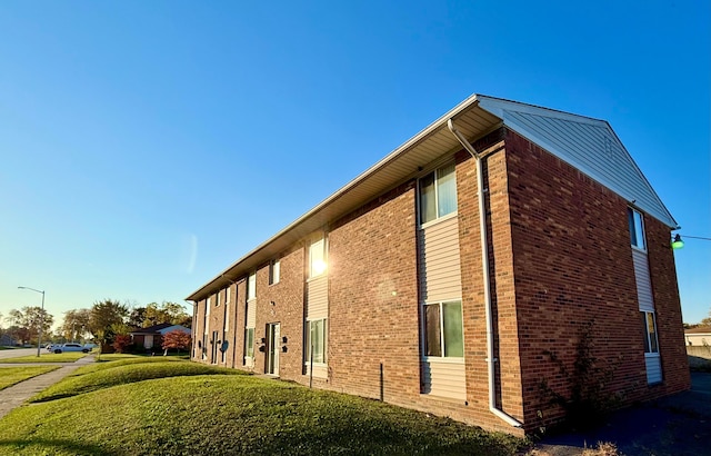 view of side of property featuring brick siding and a lawn