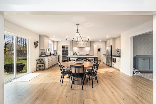 dining space with light wood-style floors, recessed lighting, baseboards, and an inviting chandelier