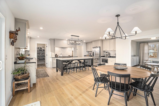 dining area featuring recessed lighting, an inviting chandelier, and light wood-style floors