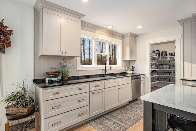 kitchen featuring recessed lighting, a sink, stainless steel dishwasher, light wood-type flooring, and dark stone counters