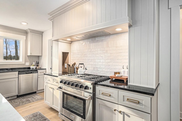 kitchen with recessed lighting, light wood-style floors, appliances with stainless steel finishes, tasteful backsplash, and custom range hood