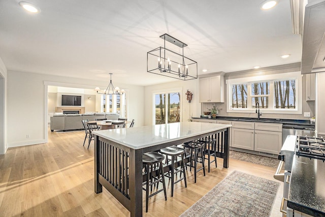 kitchen featuring recessed lighting, a sink, light wood-style floors, decorative light fixtures, and an inviting chandelier