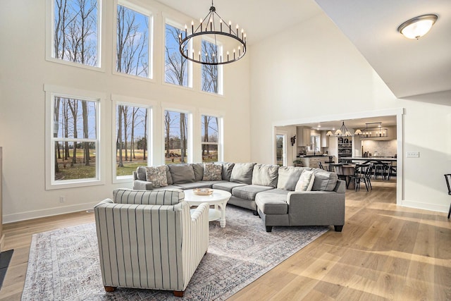 living room featuring an inviting chandelier, baseboards, and light wood-style floors