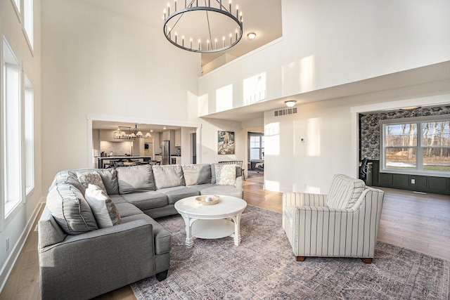 living room with a chandelier, plenty of natural light, wood finished floors, and visible vents