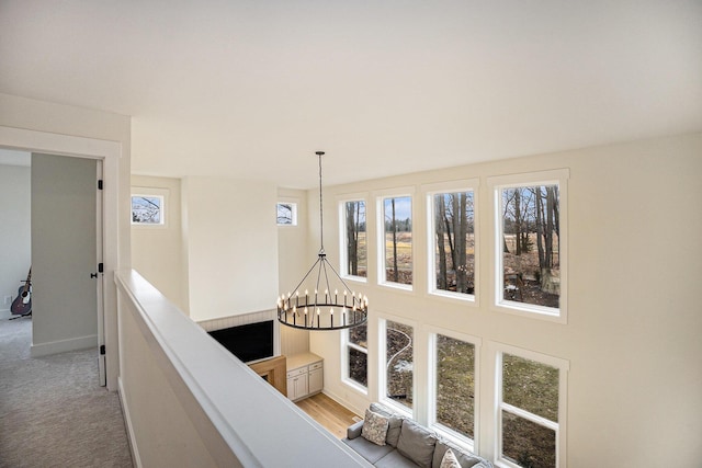 hall with light carpet, an inviting chandelier, and an upstairs landing