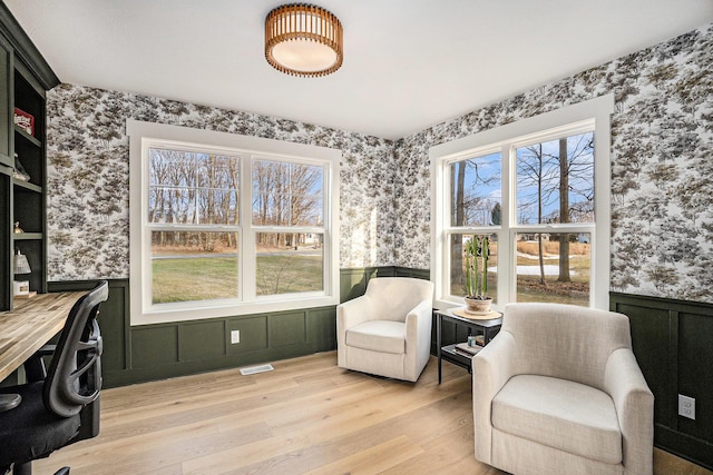 office space featuring light wood-style floors, wainscoting, visible vents, and wallpapered walls