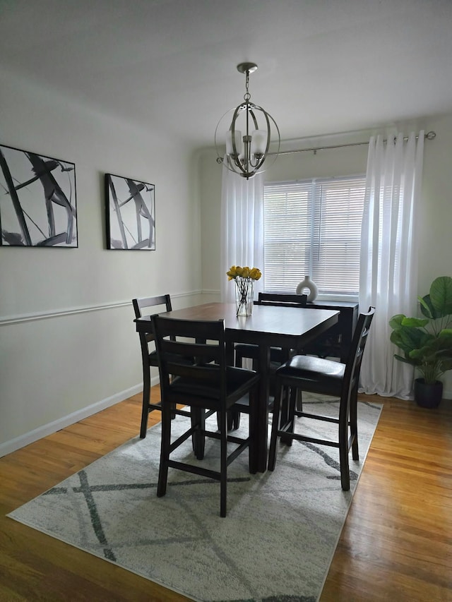 dining space featuring an inviting chandelier, baseboards, and wood finished floors