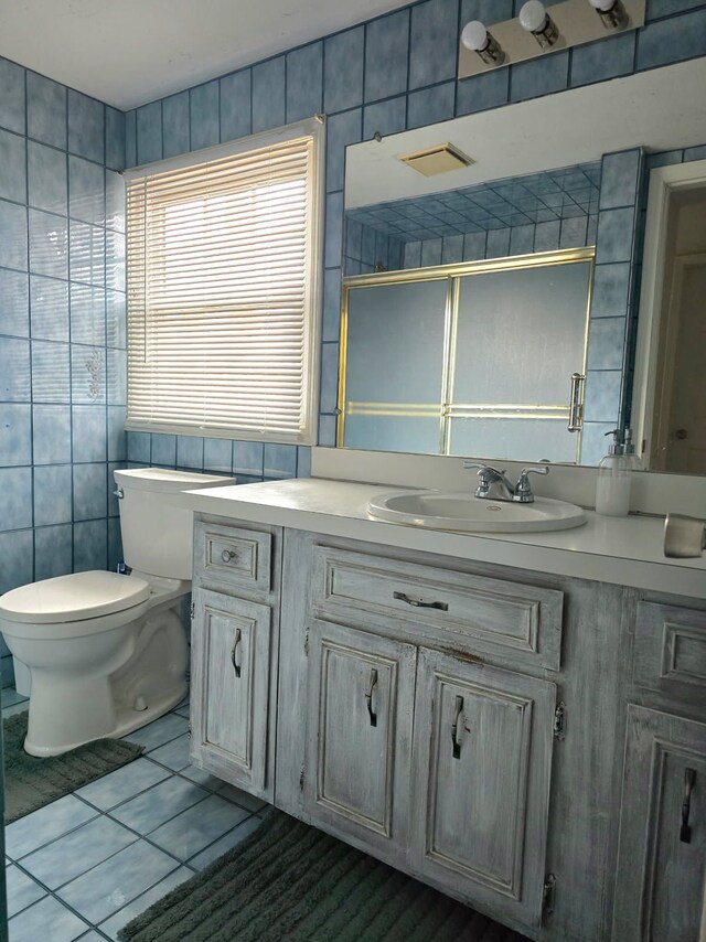 full bath with toilet, an enclosed shower, vanity, and tile walls