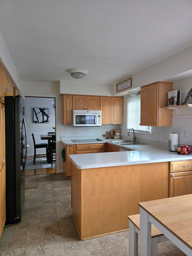 kitchen featuring tasteful backsplash, freestanding refrigerator, light countertops, electric stovetop, and a sink