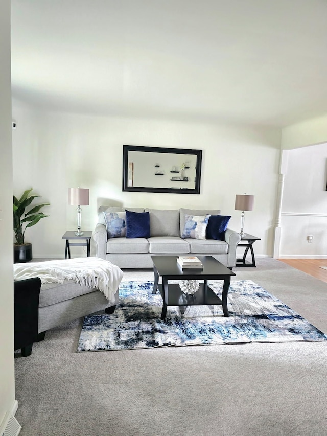 living room featuring carpet, visible vents, and baseboards