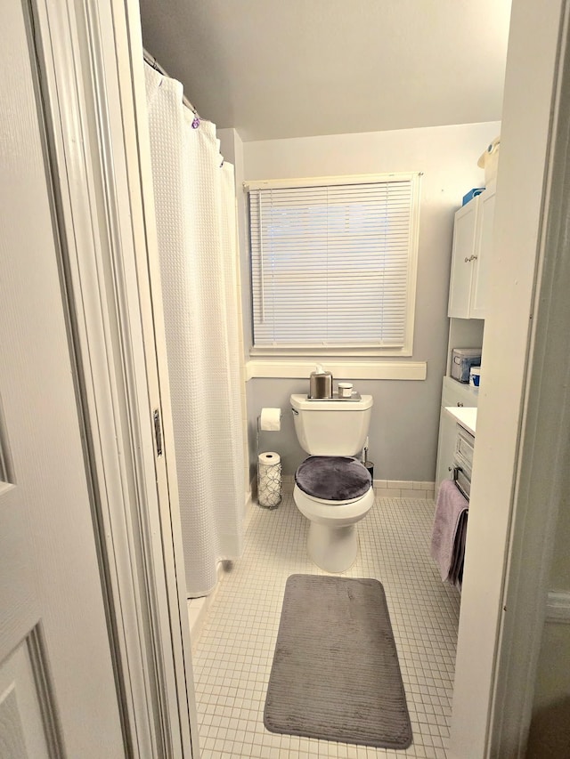 full bath featuring curtained shower, toilet, vanity, tile patterned flooring, and baseboards