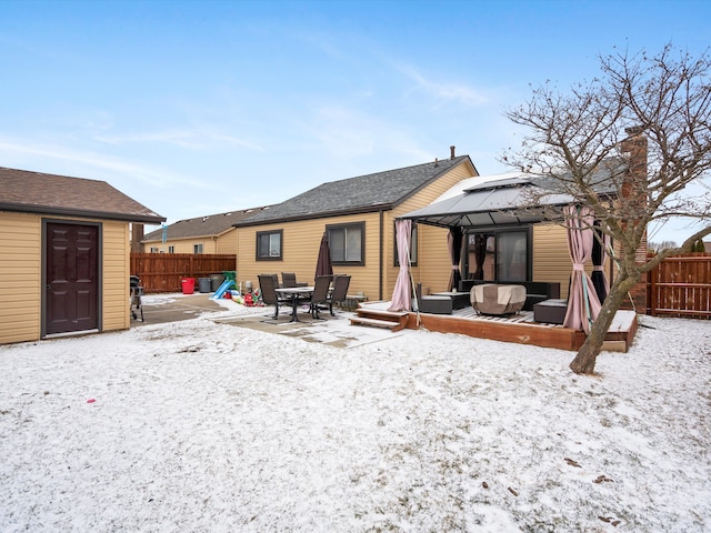 snow covered house with an outbuilding, outdoor lounge area, a gazebo, fence, and a deck