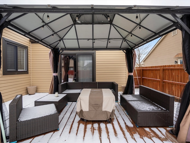 snow covered deck with fence, an outdoor hangout area, and a gazebo