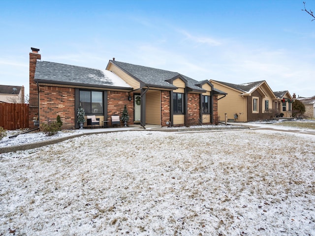 ranch-style home featuring a shingled roof, a chimney, fence, and brick siding