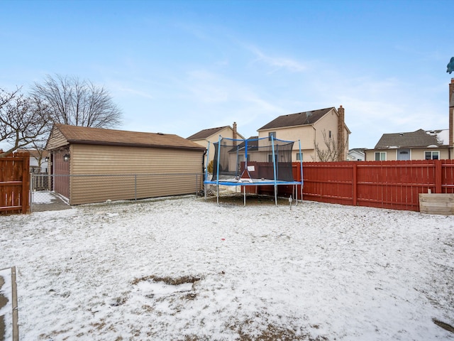 yard layered in snow with a trampoline, a residential view, and fence