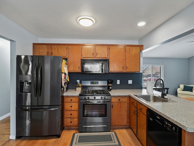 kitchen with brown cabinetry, a sink, and black appliances