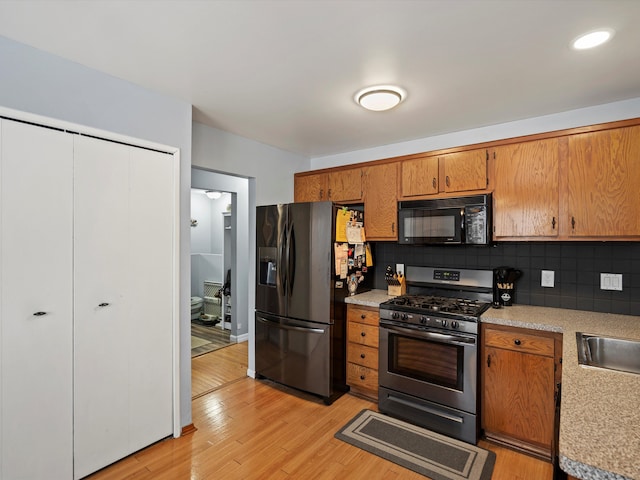 kitchen with black microwave, light countertops, fridge with ice dispenser, and gas range