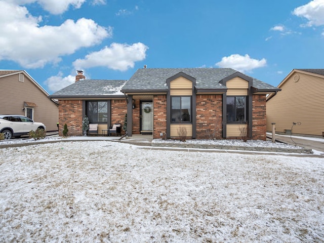 view of front of house featuring a shingled roof, a chimney, and brick siding