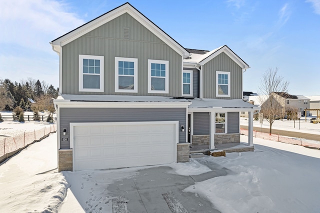 view of front of house featuring an attached garage, stone siding, fence, and board and batten siding