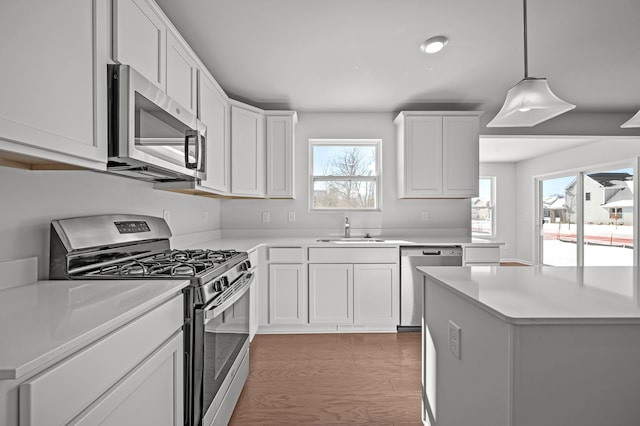 kitchen with stainless steel appliances, a sink, light countertops, and white cabinetry