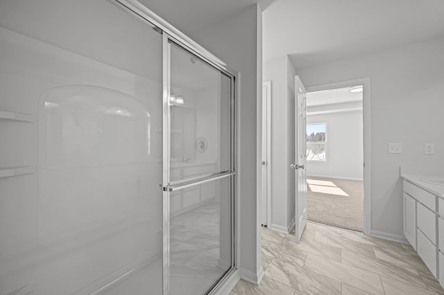 bathroom featuring vanity, a shower with shower door, and baseboards