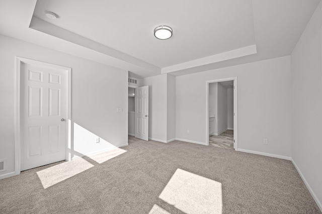 unfurnished bedroom with baseboards, a raised ceiling, and carpet flooring